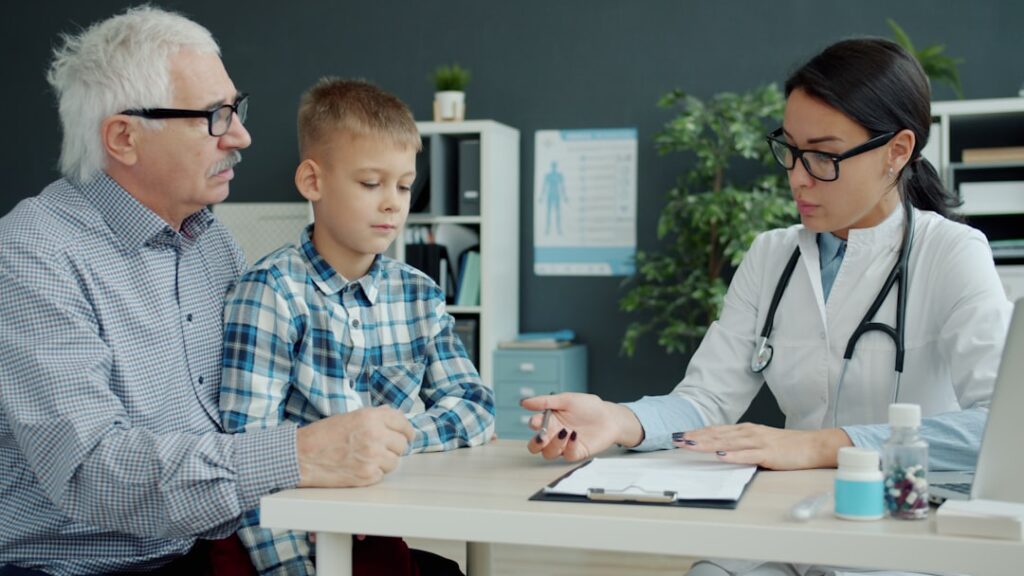 A parent comforts a young child seated at a kitchen table, both appearing engaged and calm.